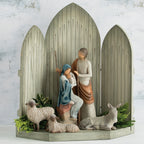 Grey barn figurine with nativity scene figurines sitting down with two white lamb figurines around them