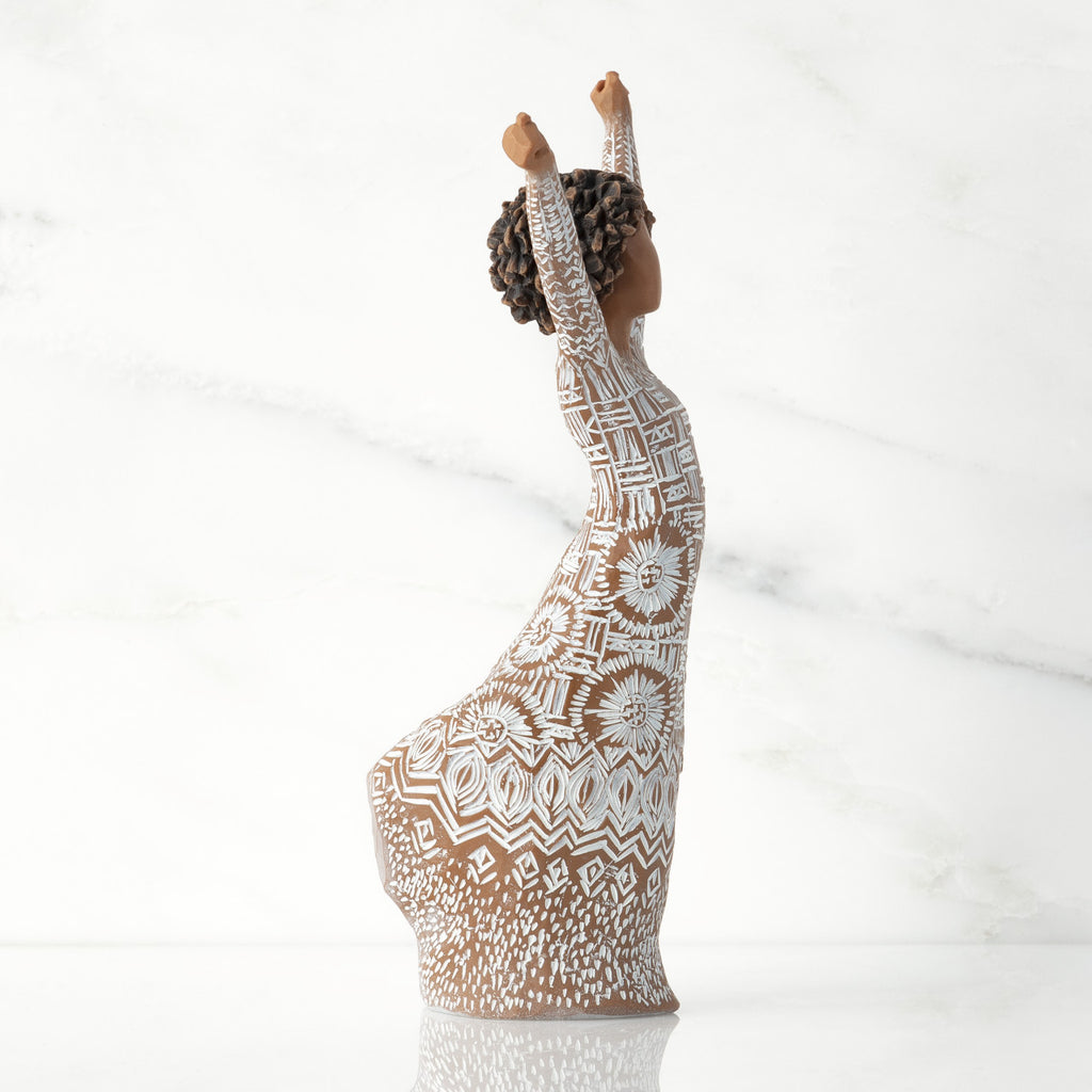 Figure facing right, with arms raised overhead, full skirt and dress etched with African textile patterns