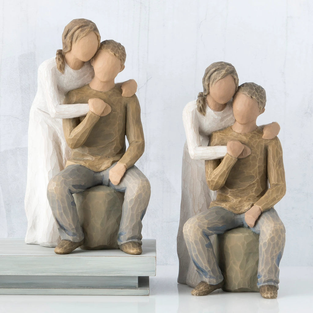 Set of two man and woman figurines sitting down with woman's arms on the man