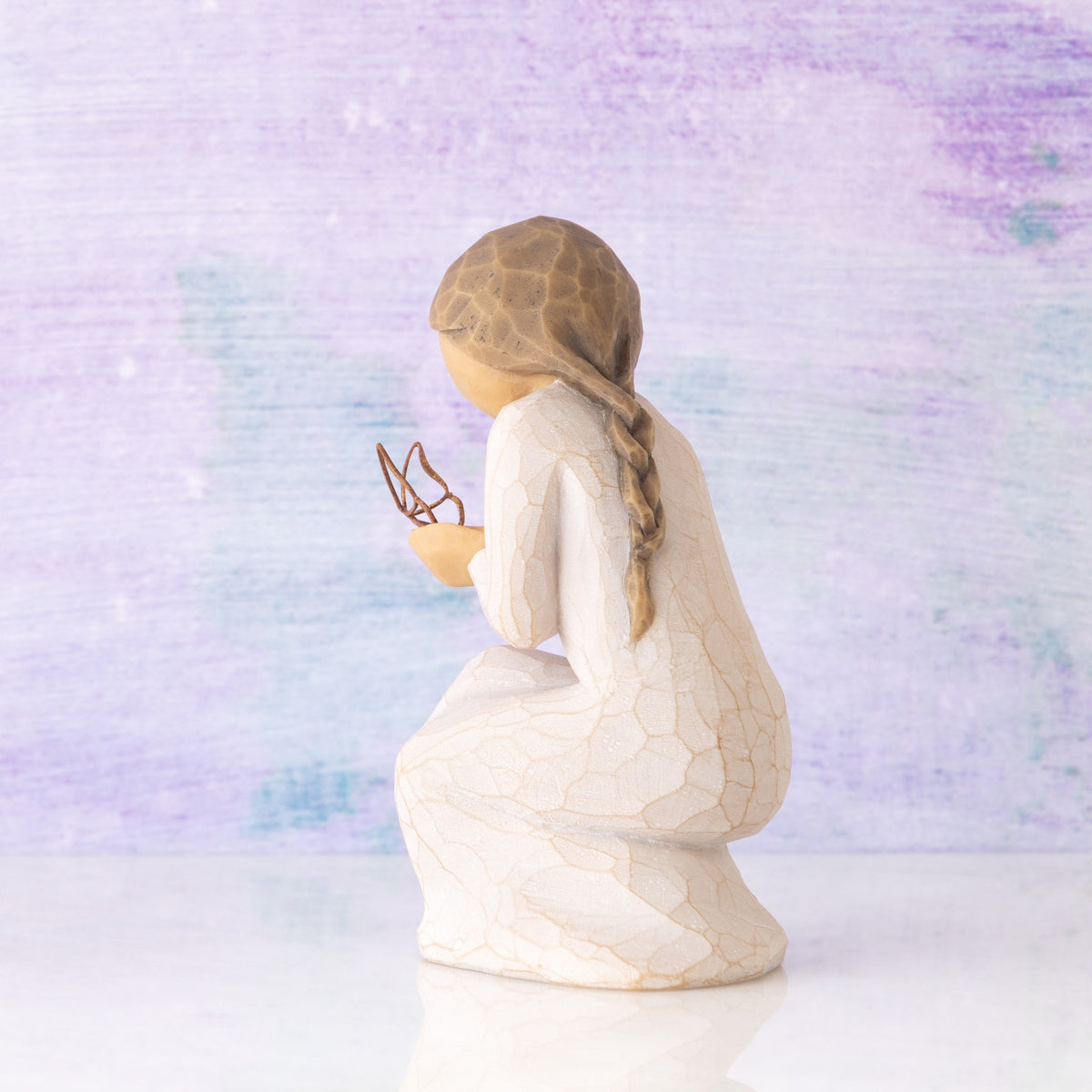 Willow Tree Quiet Wonder, 3.5”h hand-painted resin figure, kneeling in cream dress with gold leaf wire butterfly on extended hands, in front of lavender painting