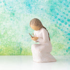 Willow Tree Quiet Wonder, 3.5”h hand-painted resin figure, kneeling in cream dress with gold leaf wire butterfly on extended hands, in front of blue green painting