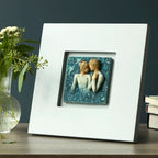 Willow Tree Duet, 10”sq hand-painted dove gray wood frame, with inset bas-relief resin plaque of embracing couple, surrounded by nature, blue ombré background with gold leaf, sitting on table
